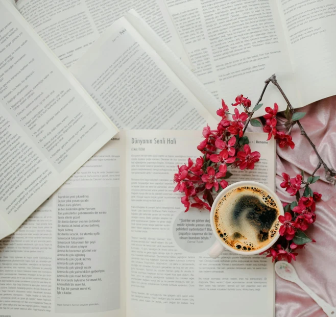 a cup of coffee and some books with red flowers