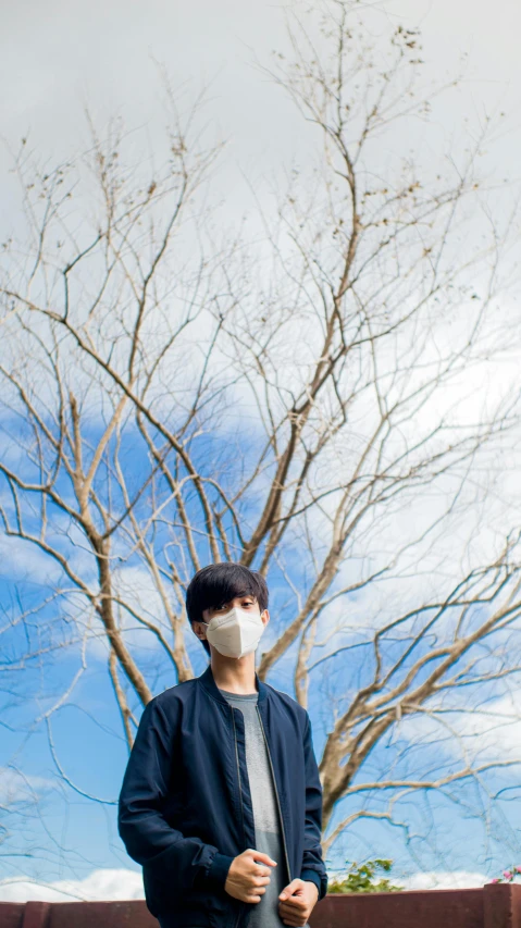 man wearing mask while standing in front of tree