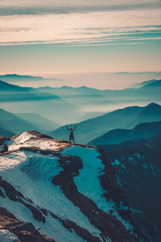 the man on the top of a mountain is making a weird gesture