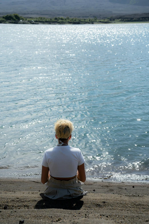 the woman sits at the edge of the water on her back