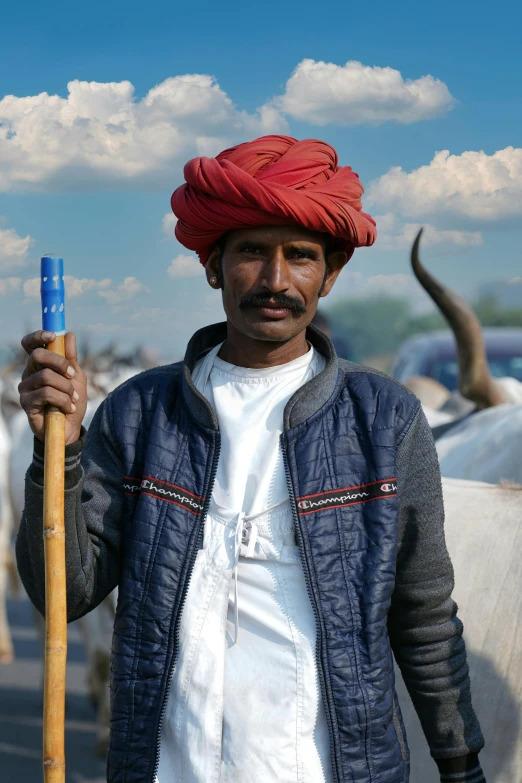 a man holding a large blue stick in front of cattle