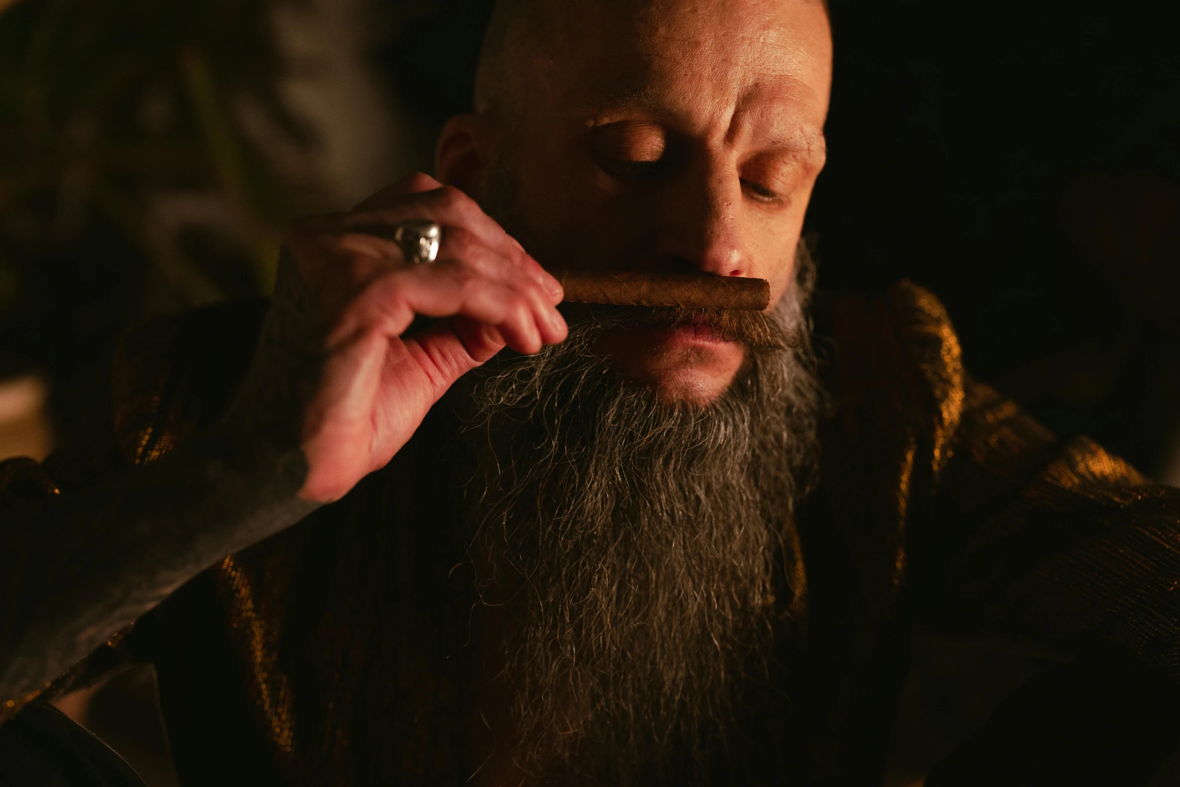 a bearded man with his eye open and a cigarette in his hand