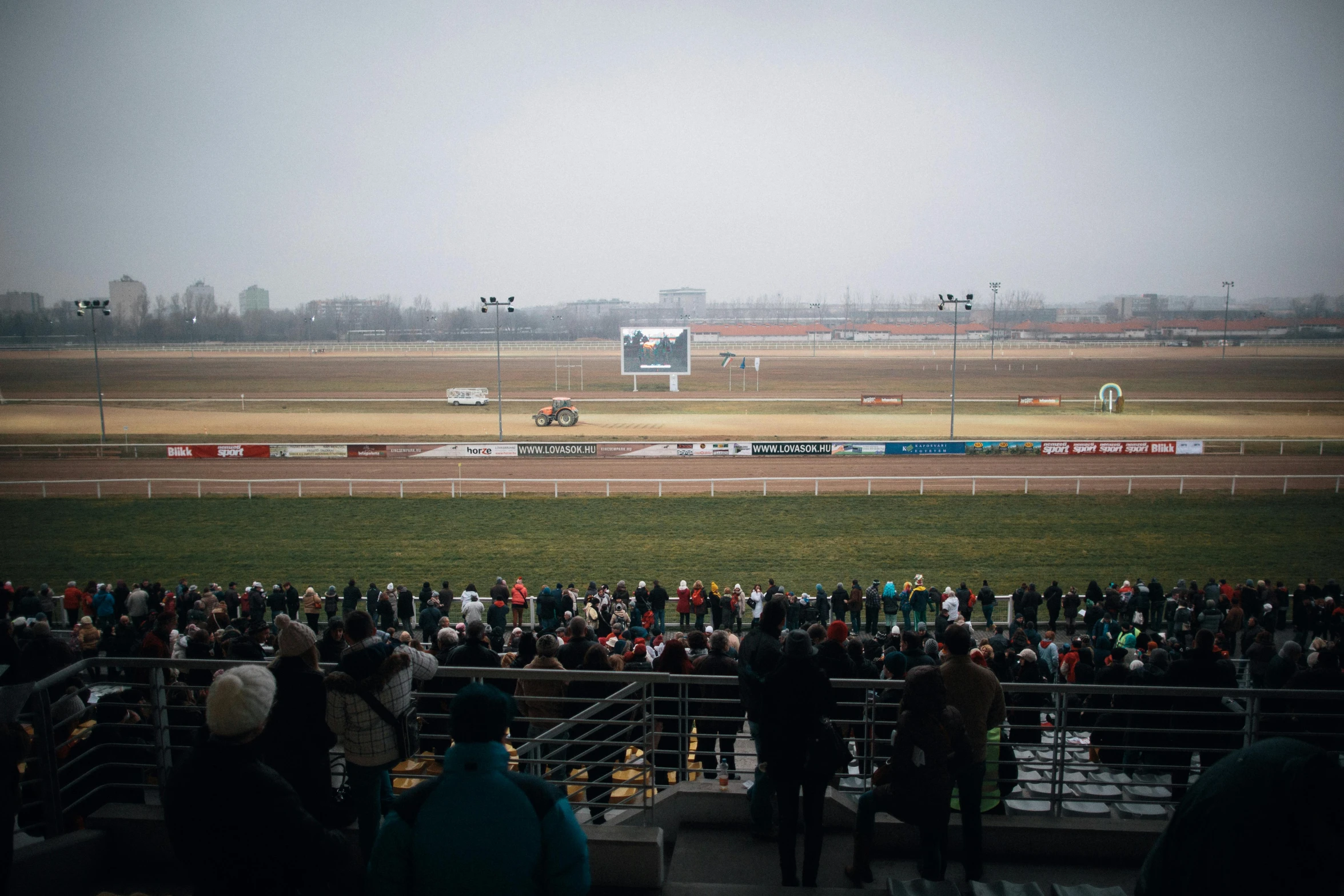 a large crowd watches the racing at the track