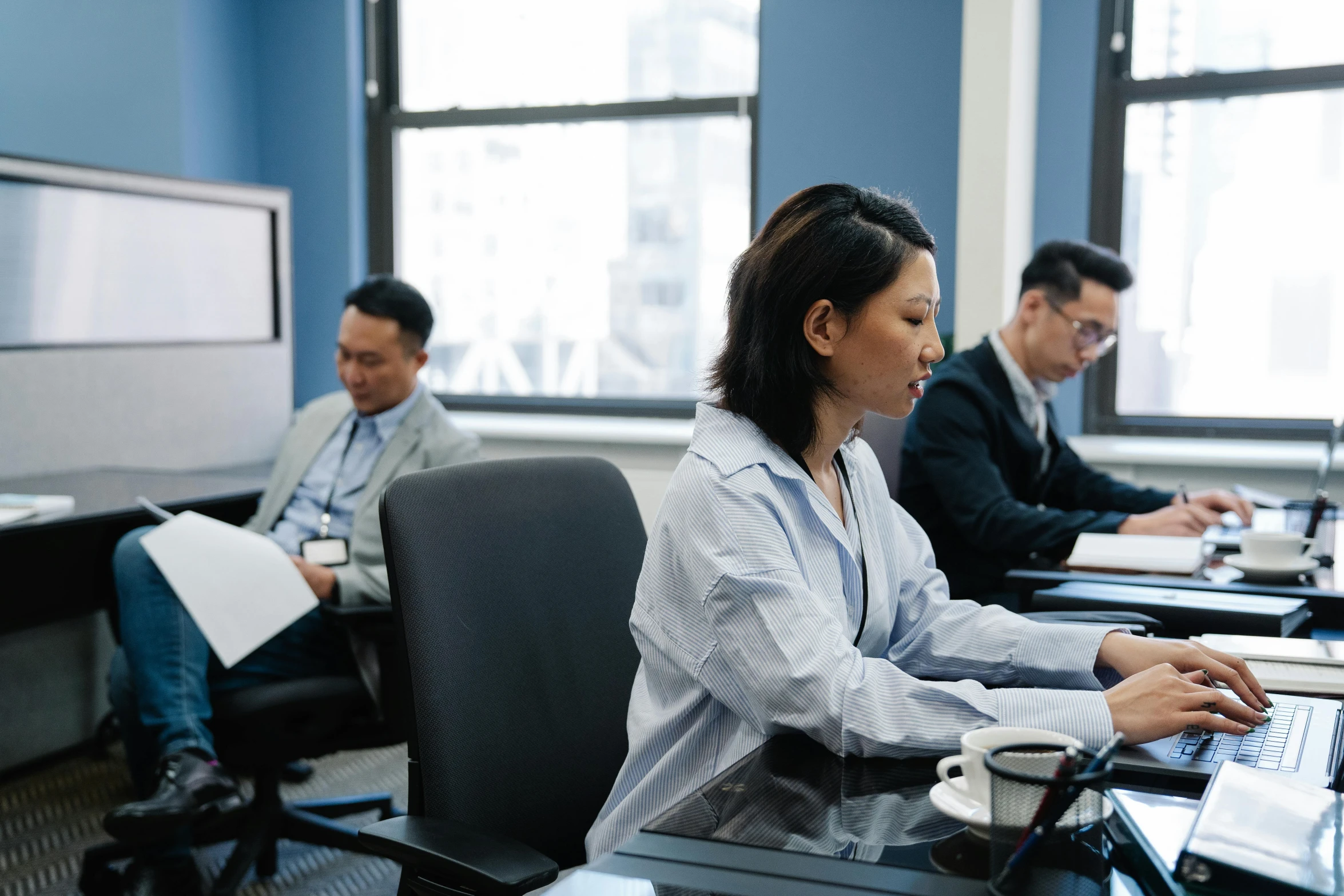 people sit in an office setting on their laptops