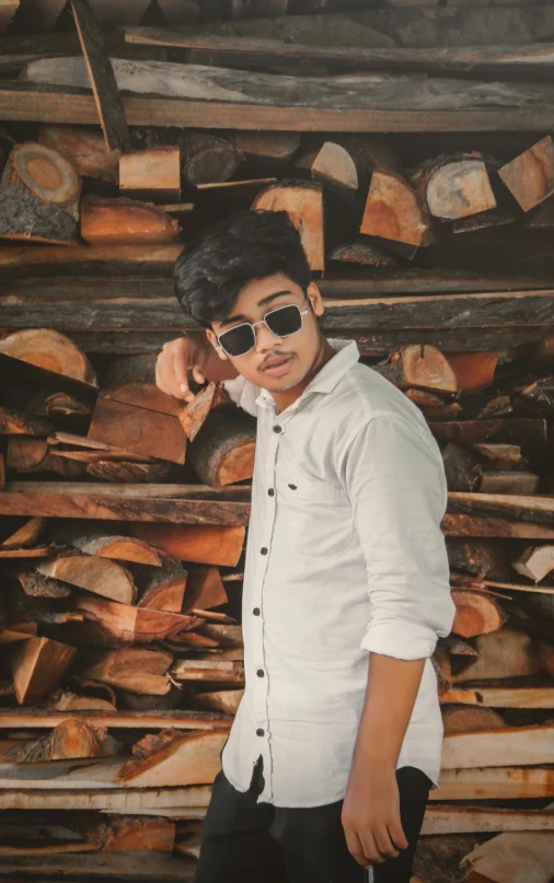 a young man in sunglasses standing next to wood