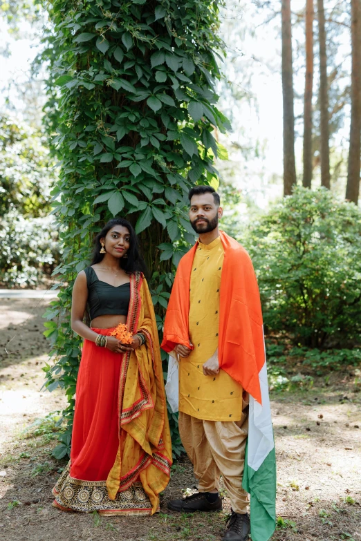 man and woman in indian outfits standing under a tree