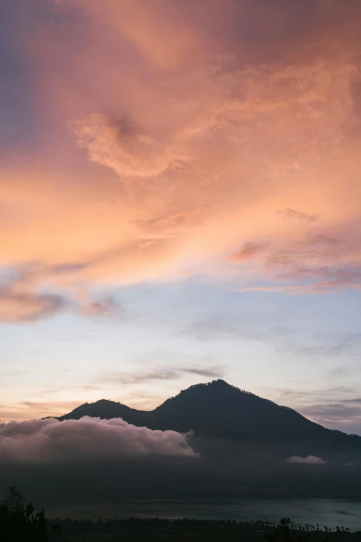 some clouds are coming over a very tall hill