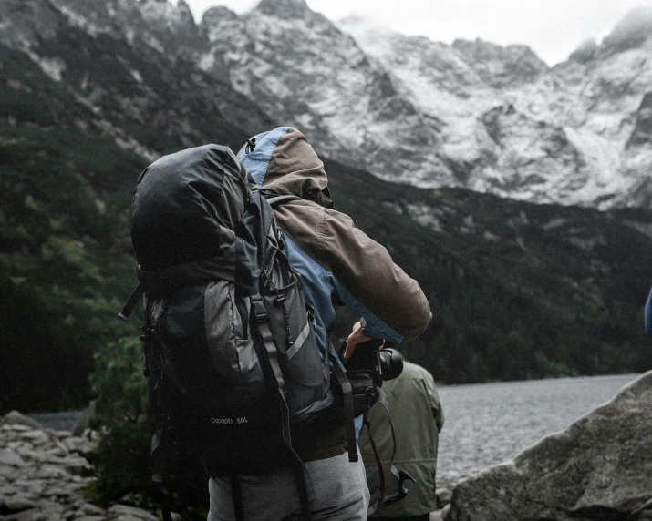 two men are standing near some mountains with a lake in the middle