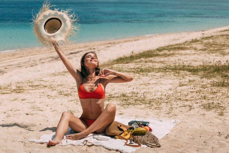 a beautiful young woman sitting on top of a sandy beach