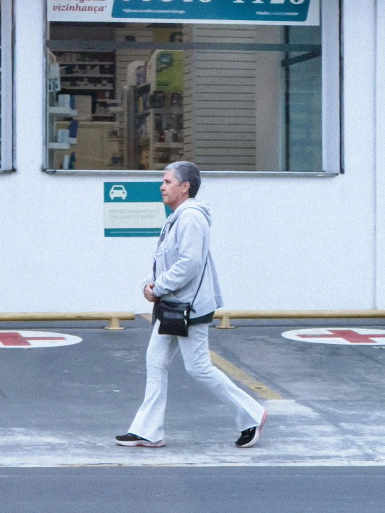 a man crossing the street in front of a business