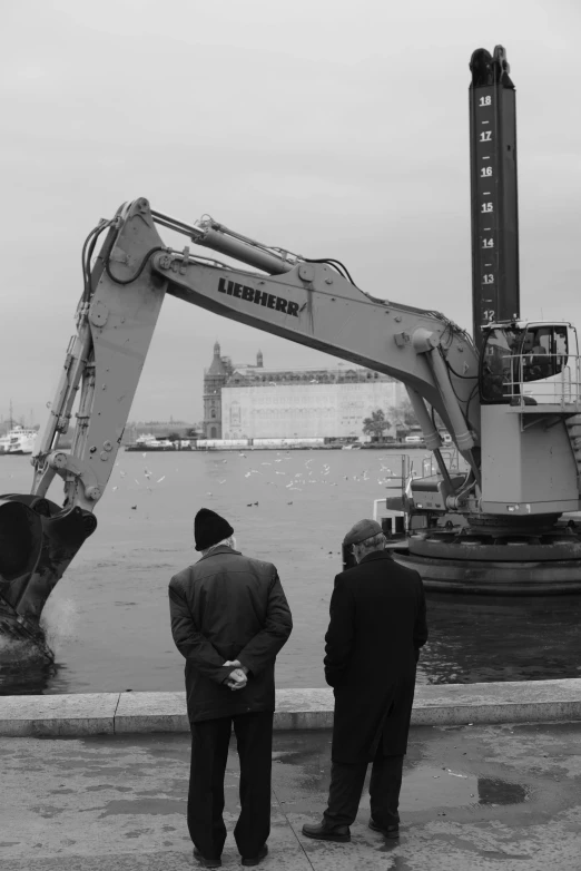 two men stand at the water's edge near an old boat