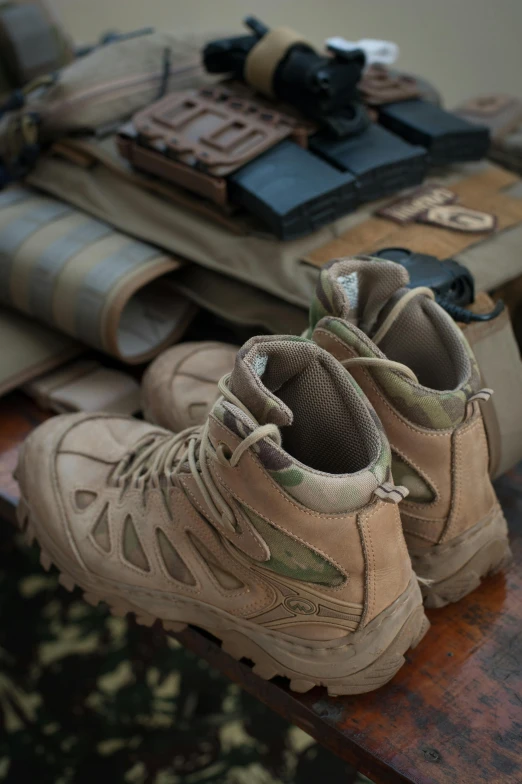 a pair of combat style hiking boots sit atop military gear