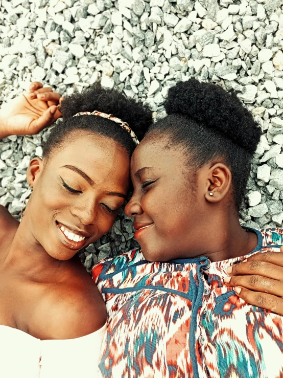 two women smile together as they lie next to each other