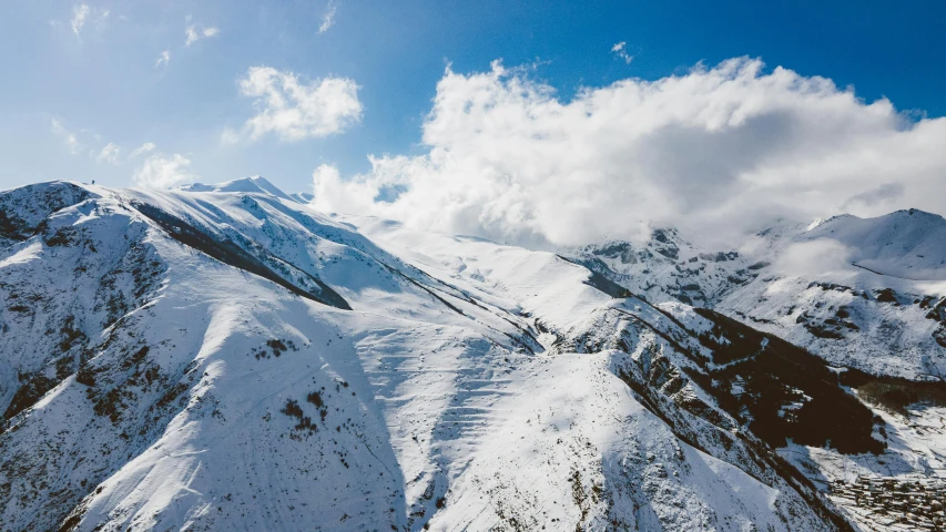 a snow covered mountain under a cloudy blue sky