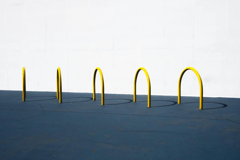 a row of yellow metal curved lines next to a wall