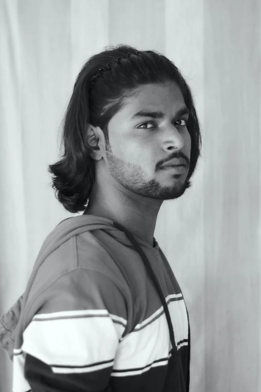 a man with long hair and  in front of a curtain