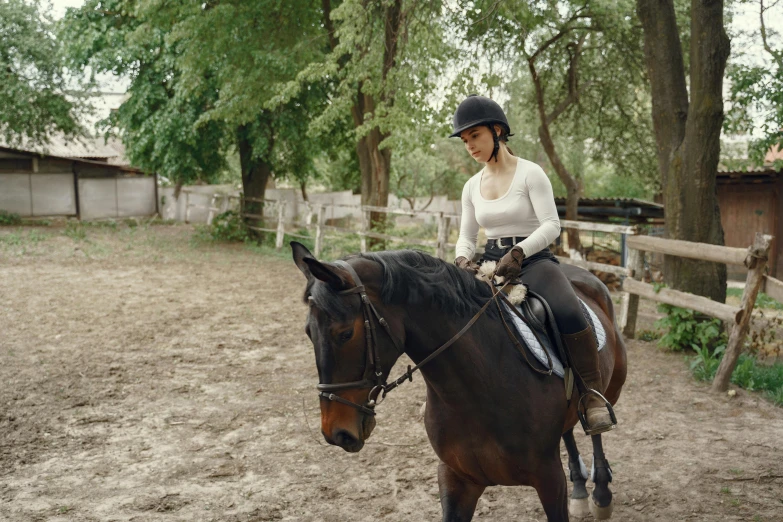 a woman rides a horse in an enclosure