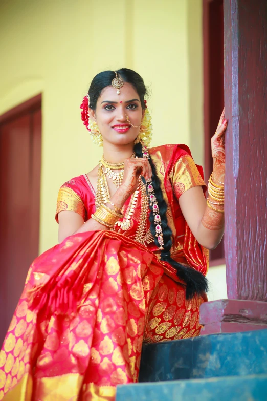 a woman with red and gold saree holding a umbrella