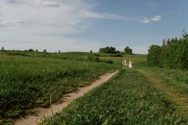 the two people walk along the trail through the grassy area