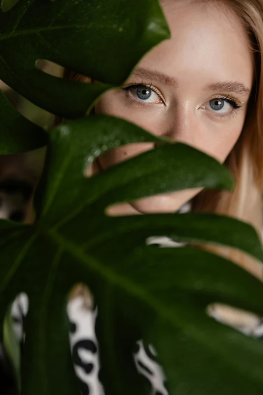 a woman's face looking over a green plant