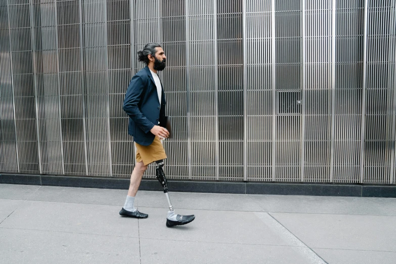 the man is walking down the sidewalk with a scooter