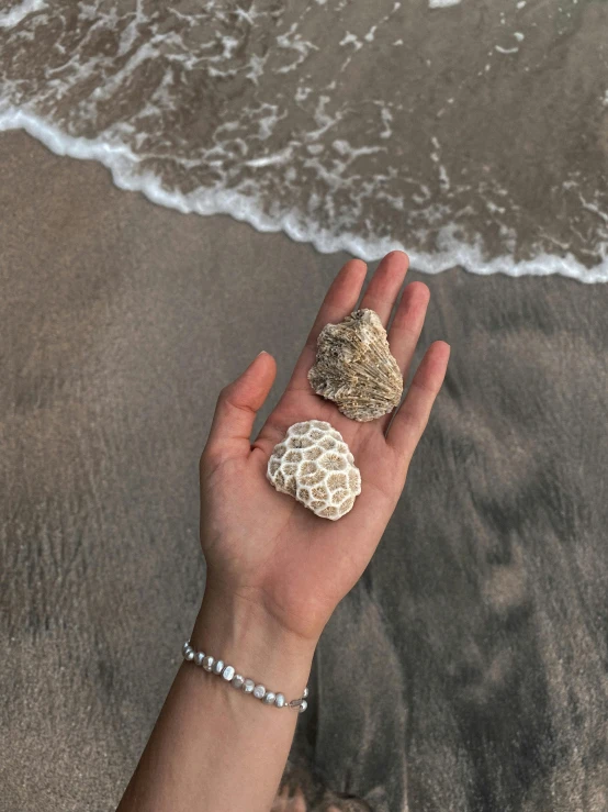 a woman's hand with two rings on it near the ocean