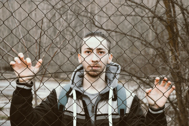 a man looking through the fence at a forest