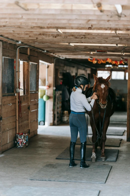 a woman on a horse that is in a stable