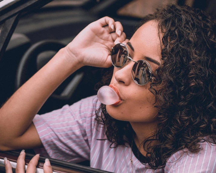 a woman with sunglasses and an ice lolly sticks out of her mouth