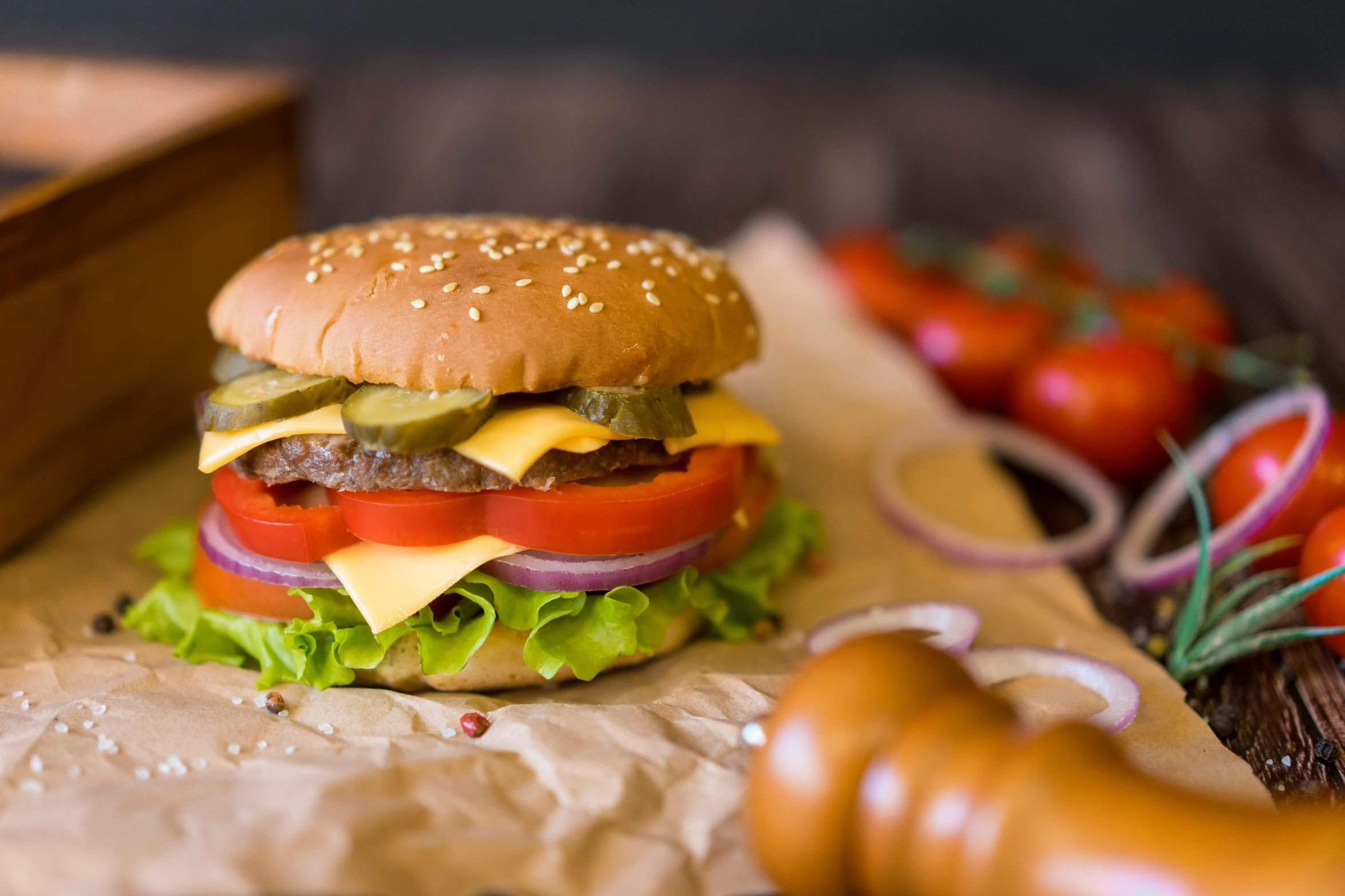 a cheeseburger with tomatoes, lettuce, cucumber, onions and pickles