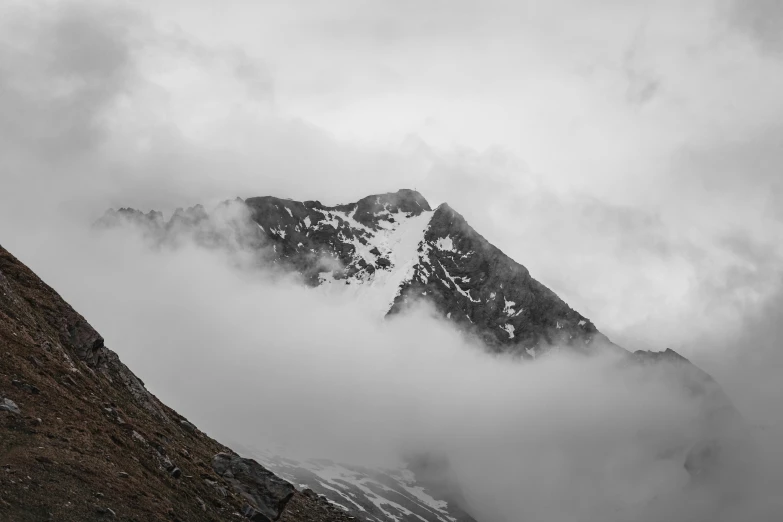 mountain peaks are shrouded by the clouds in a black and white po