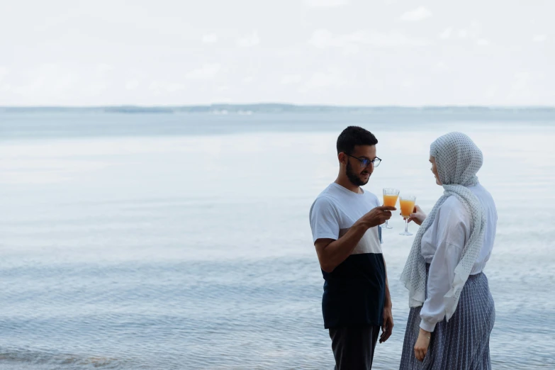 a man and woman standing at the beach on a sunny day with cocktail