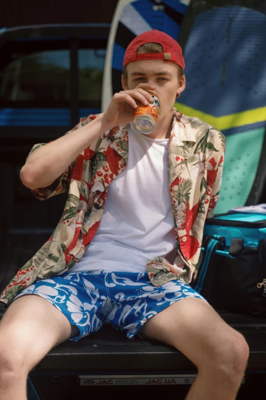 a young man sitting in the bed of his truck, drinking a beer