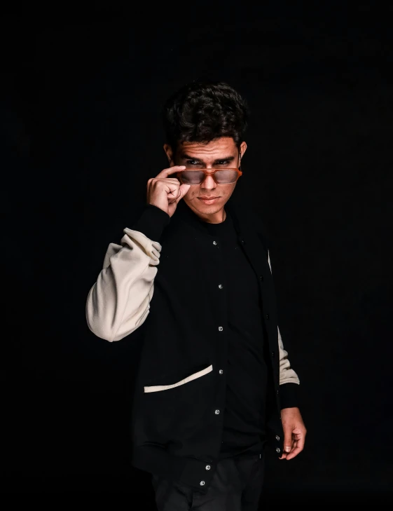 man in black holding eyeglasses to one side and his right hand on the temple