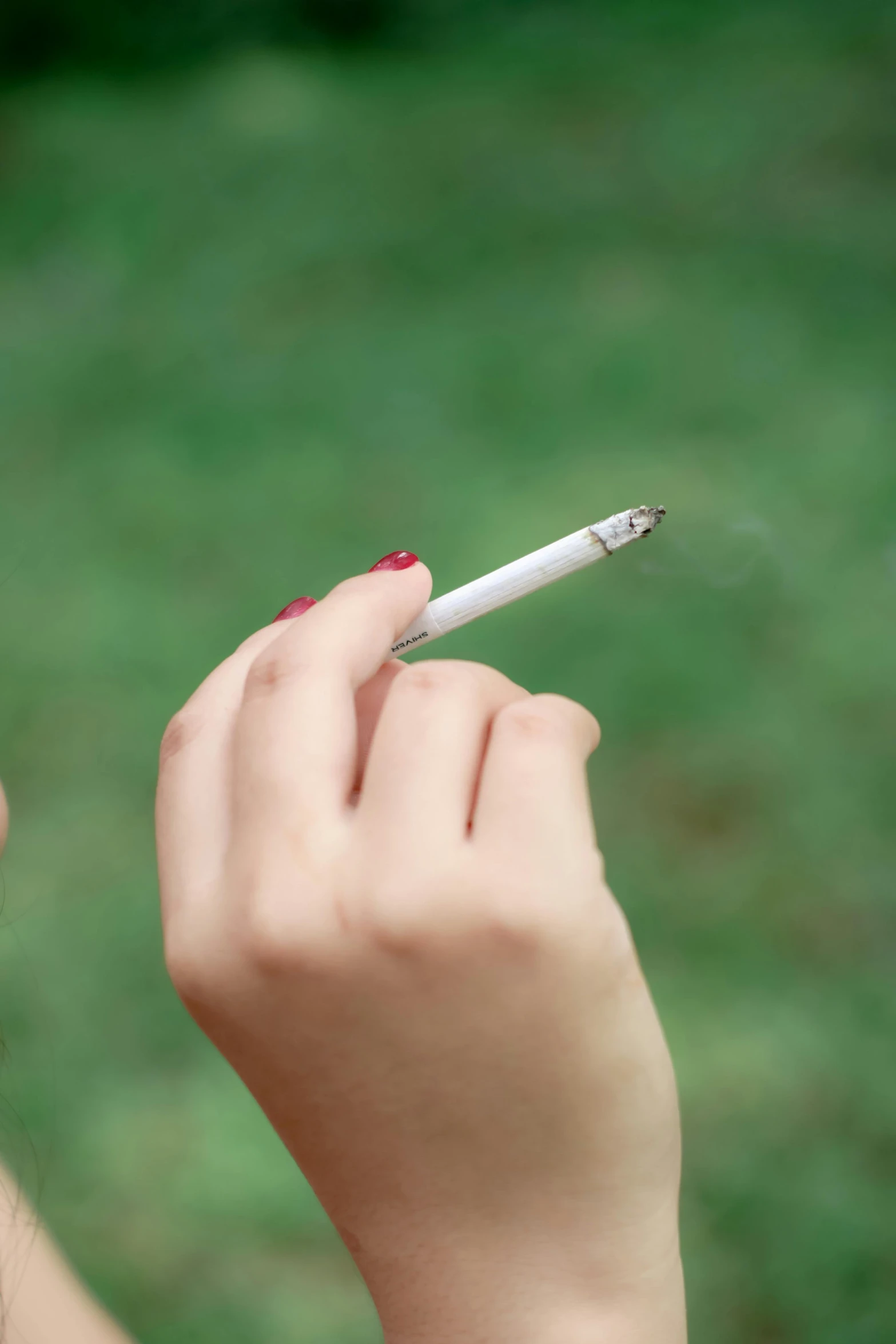 a woman holding a cigarette with one hand and smoking soing