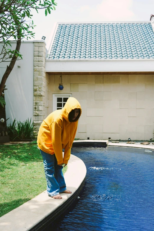 a boy in a yellow hoodie next to a pool