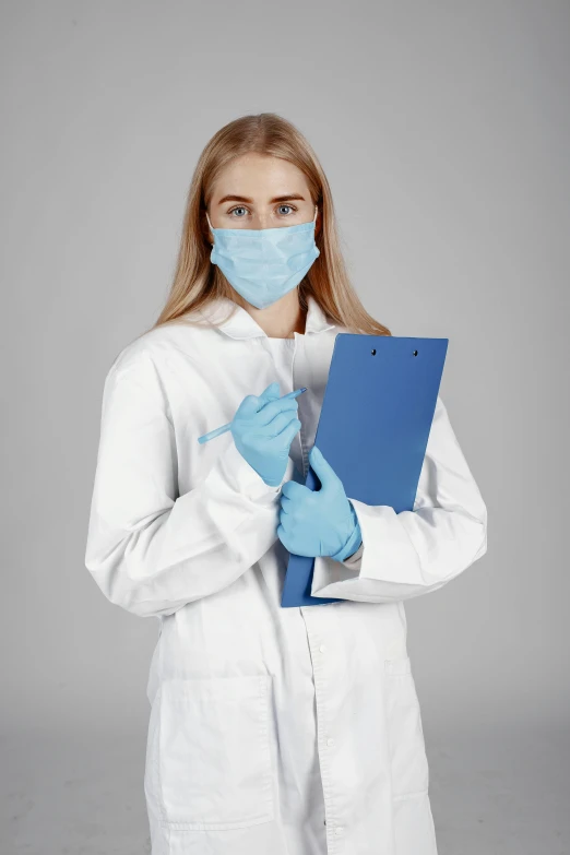 a woman in white coat and blue gloves holding a binder over her face