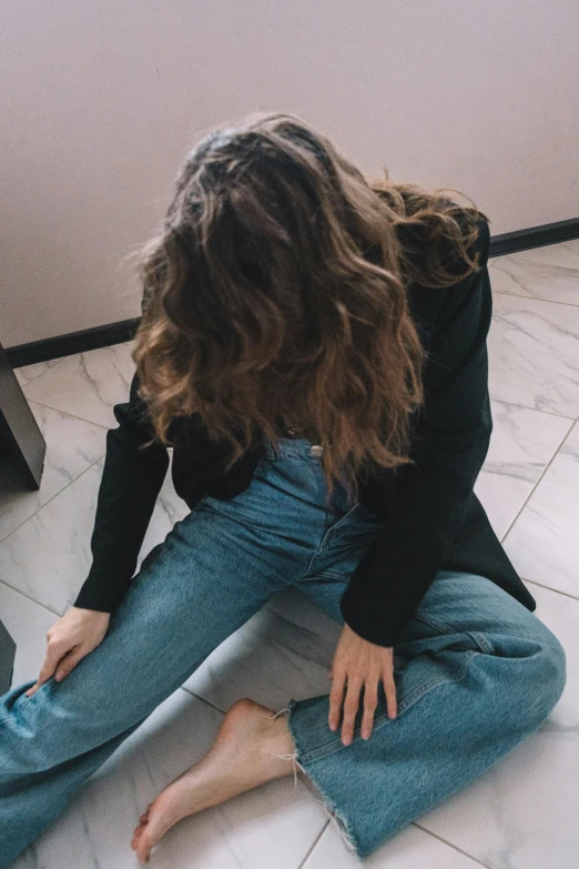 a woman sitting on the floor and looking down at her shoes