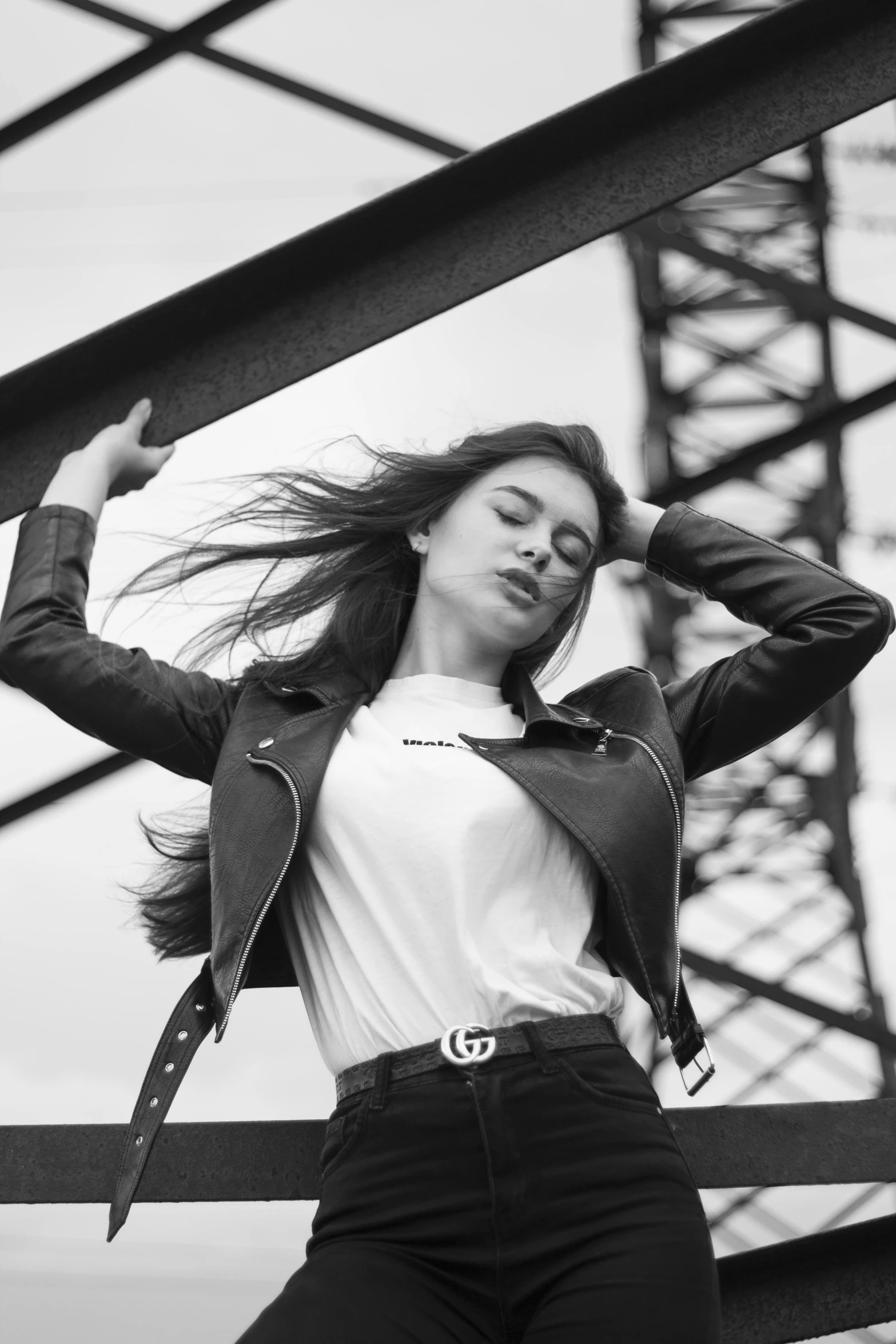 a woman posing near a large building holding her hair