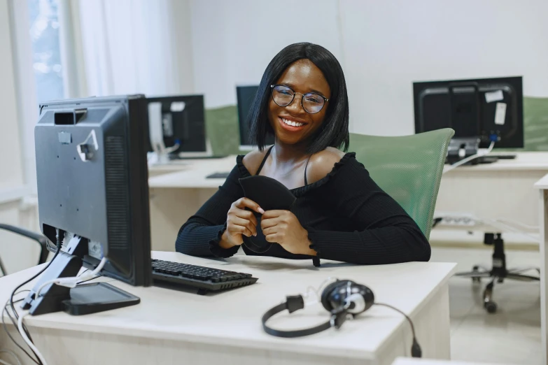 woman sitting at table in front of computer monitor