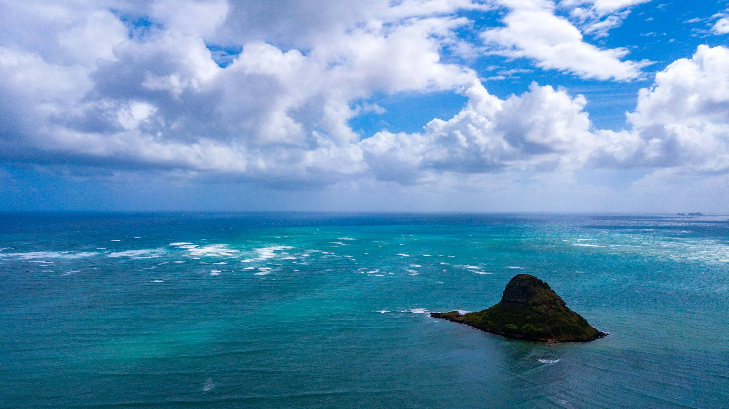 a blue ocean that is under some clouds