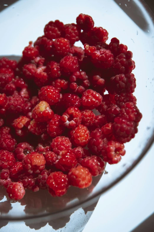 a plate full of raspberries in a glass bowl