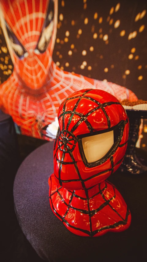 a red spiderman mask sits on top of a wooden table