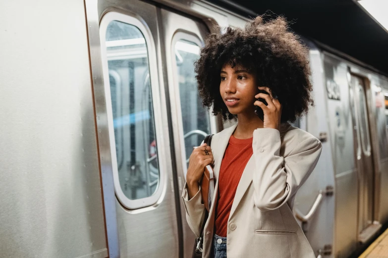 woman standing with phone near train, looking into camera