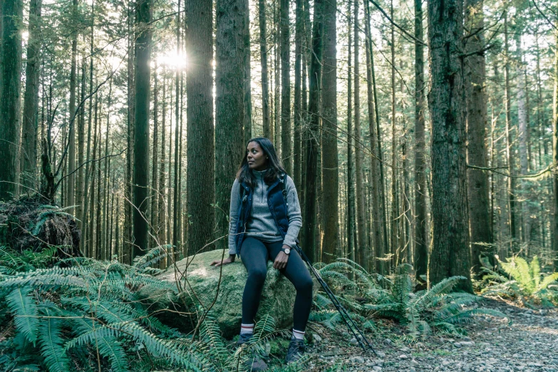 a young woman stands in the middle of a forest