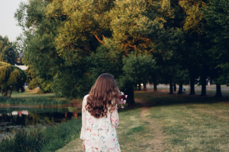 a woman is walking along a path with trees near by