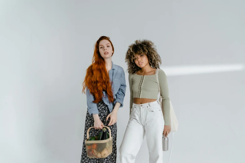 two women standing near one another and one holding a basket