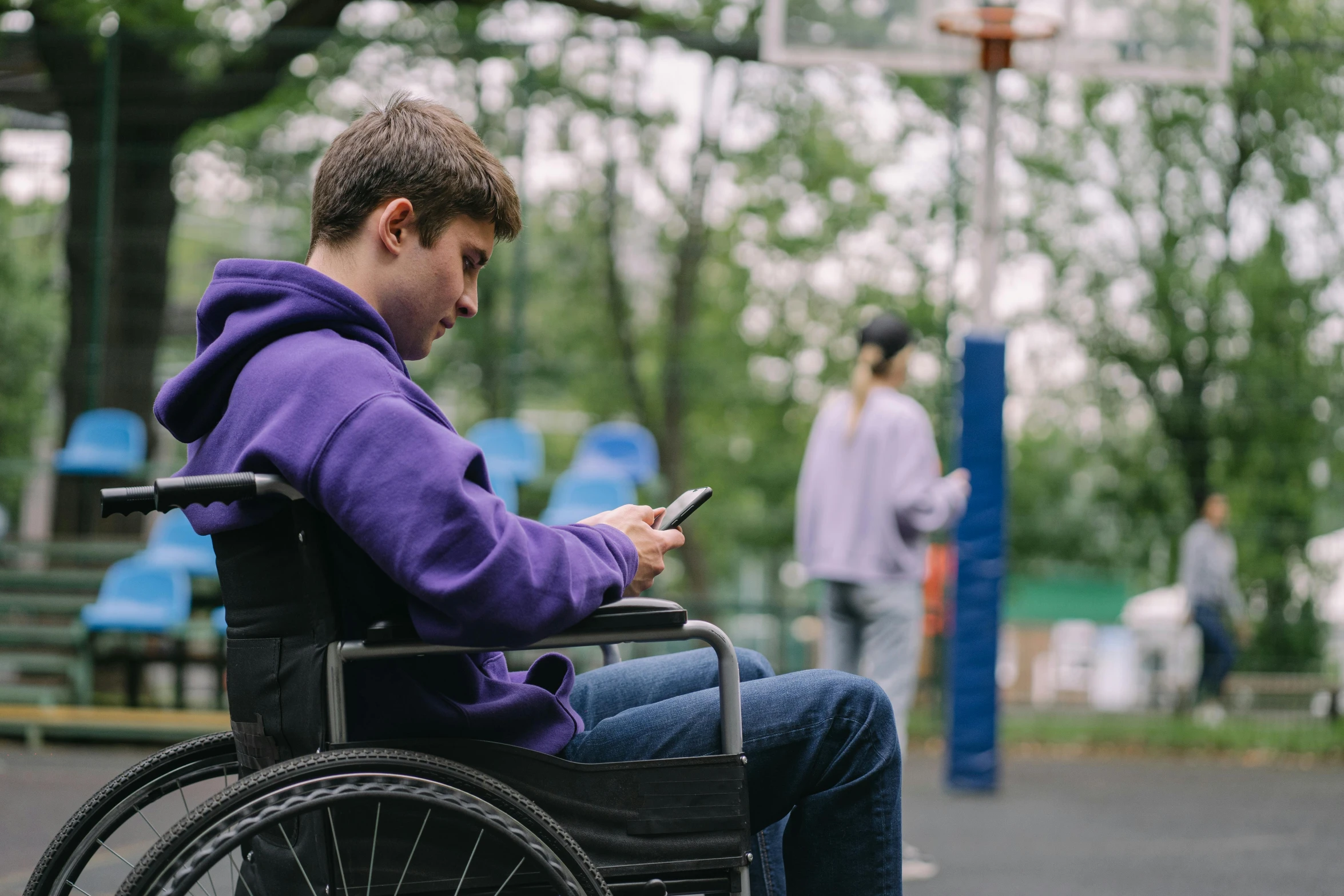 a man in a wheelchair, using his cell phone