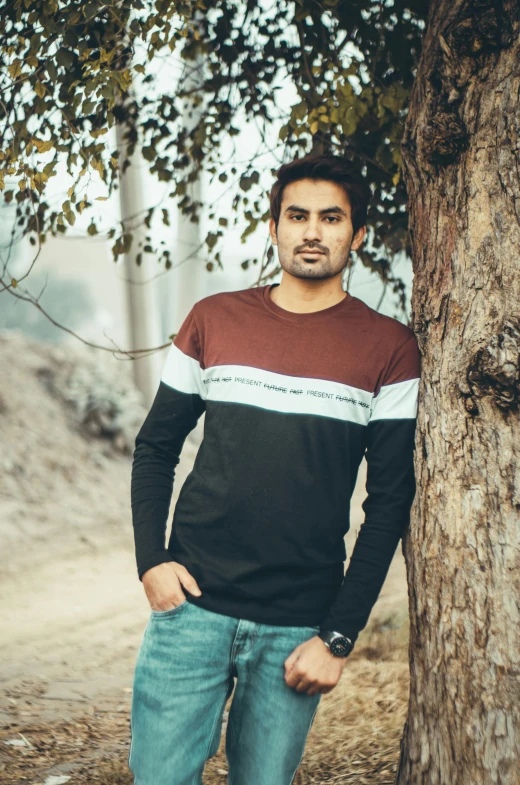 man leaning against tree in front of dirt path