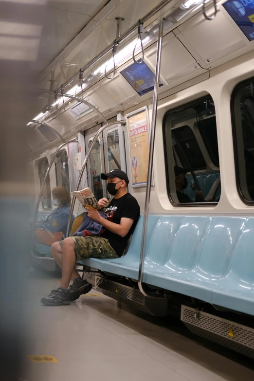 man sitting on the subway reading a newspaper